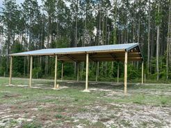 A wooden structure with a metal roof is sitting in the middle of a field.