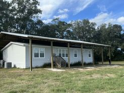 A white mobile home with a covered porch in a grassy field.