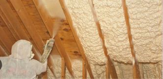 A man is spraying foam on the ceiling of a house.
