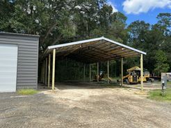 A carport with a tractor parked underneath it.
