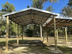 A carport is being built in a field with trees in the background.
