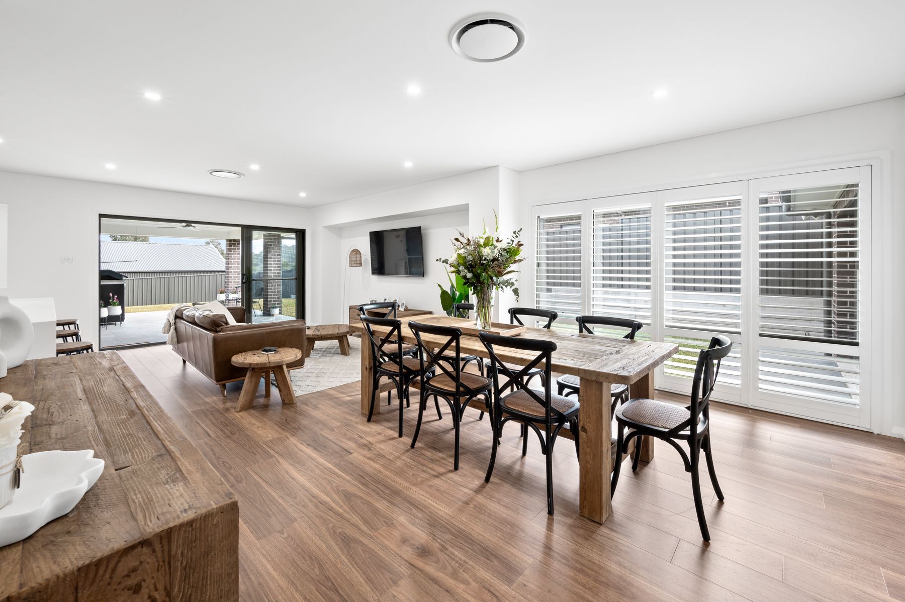 There is a dining table and chairs in the middle of the room — Plantation Shutters in Singleton, NSW