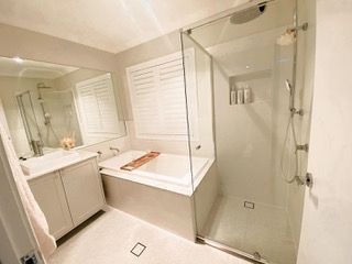A bathroom with a tub , sink , shower and mirror — Plantation Shutters in Singleton, NSW