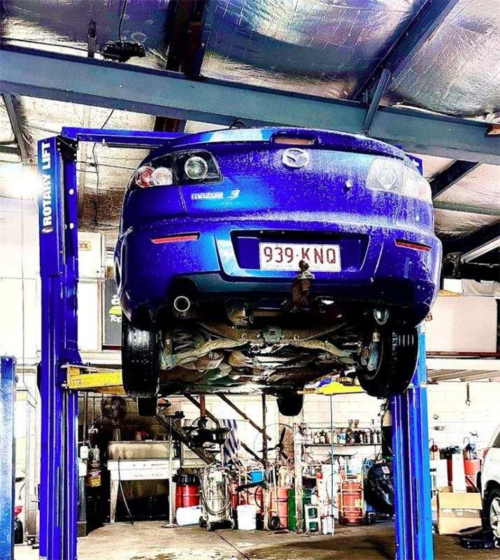 A Blue Car Is Sitting On A Lift In A Garage — Baker Automotive In Bungalow, QLD