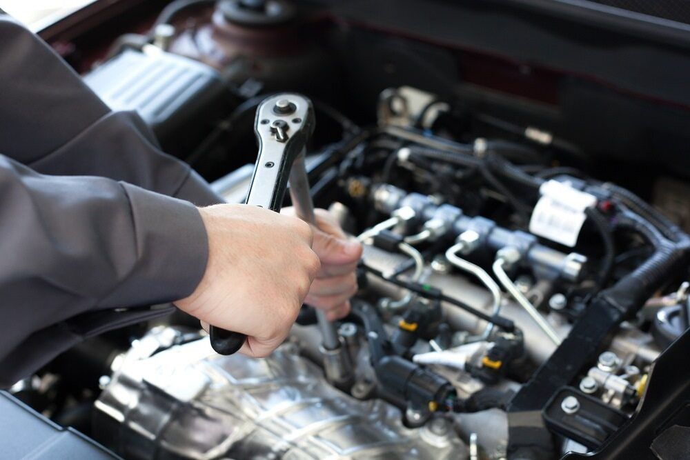 A Person Is Working On A Car Engine With A Wrench — Baker Automotive In Bungalow, QLD