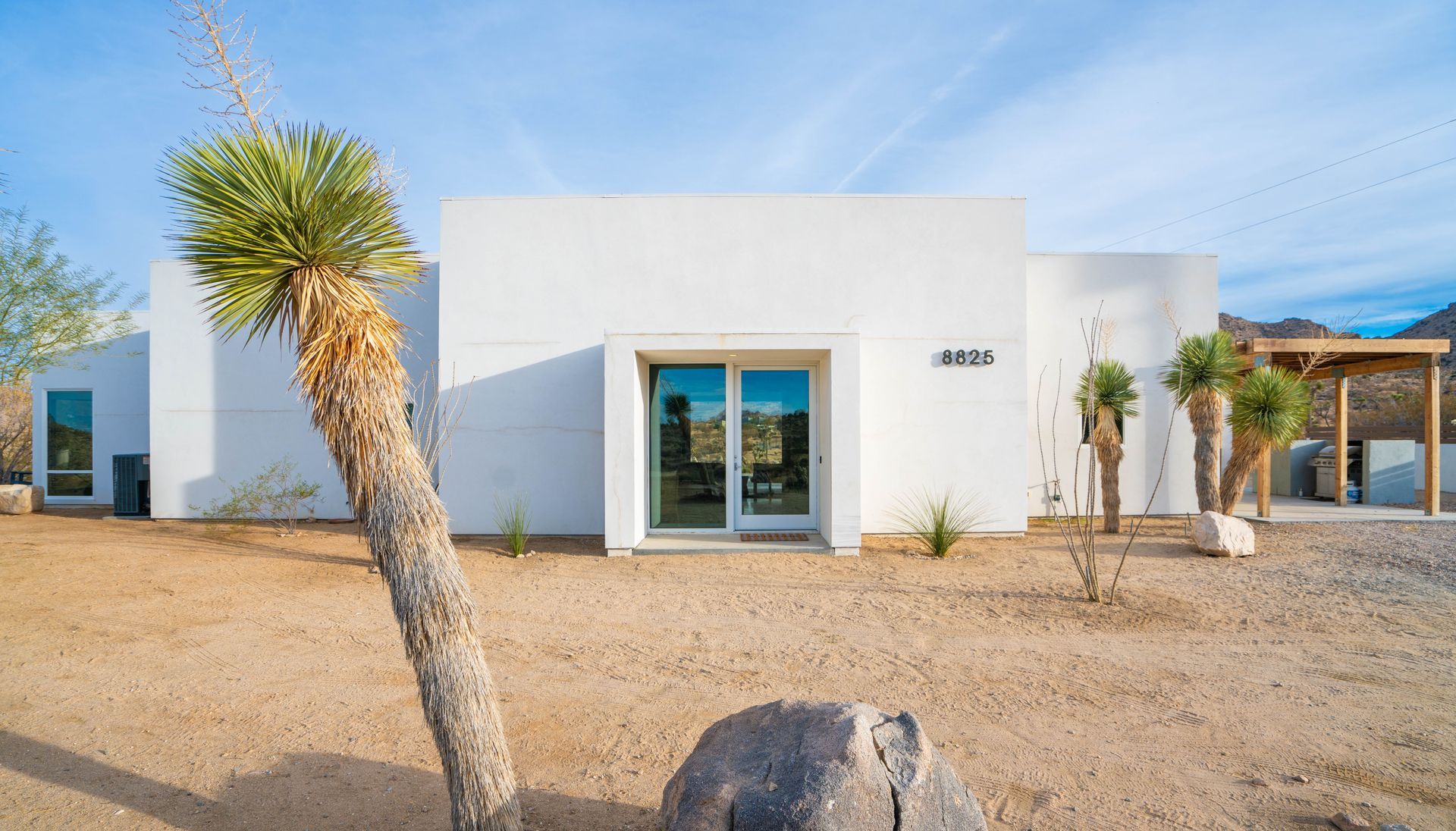 White modern house in desert landscape with Joshua tree.