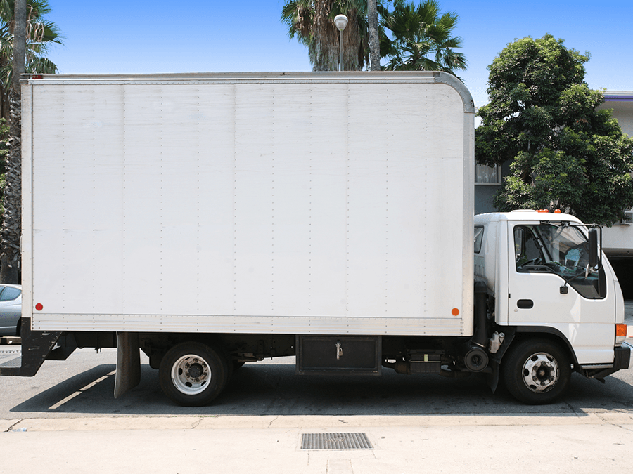 A white moving truck is parked on the side of the road.