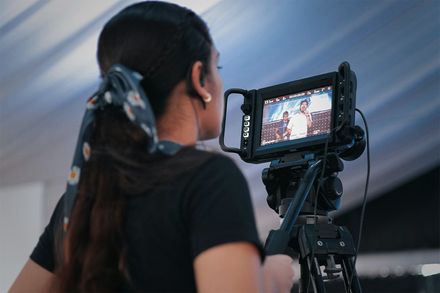 A woman behind the lens on a video production shoot.