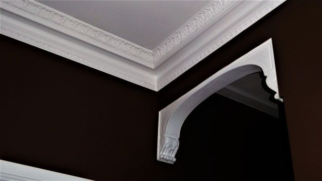 A corner of a room with white molding and a brown wall