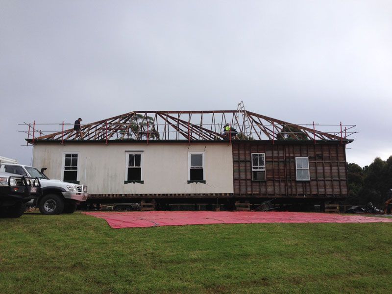 A white truck is parked in front of a house that is being moved.