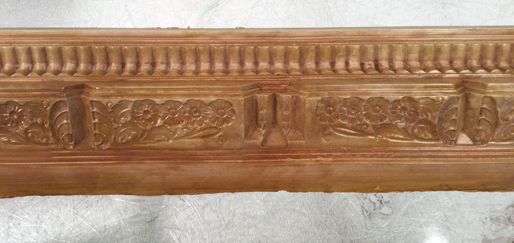 A close up of a wooden molding on a white surface.