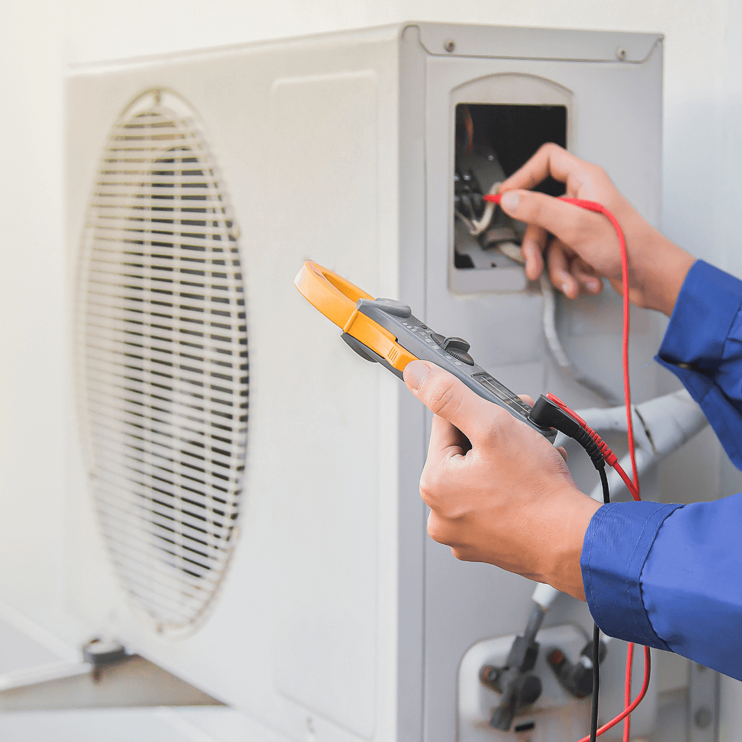A person is working on an air conditioner with a pair of pliers.