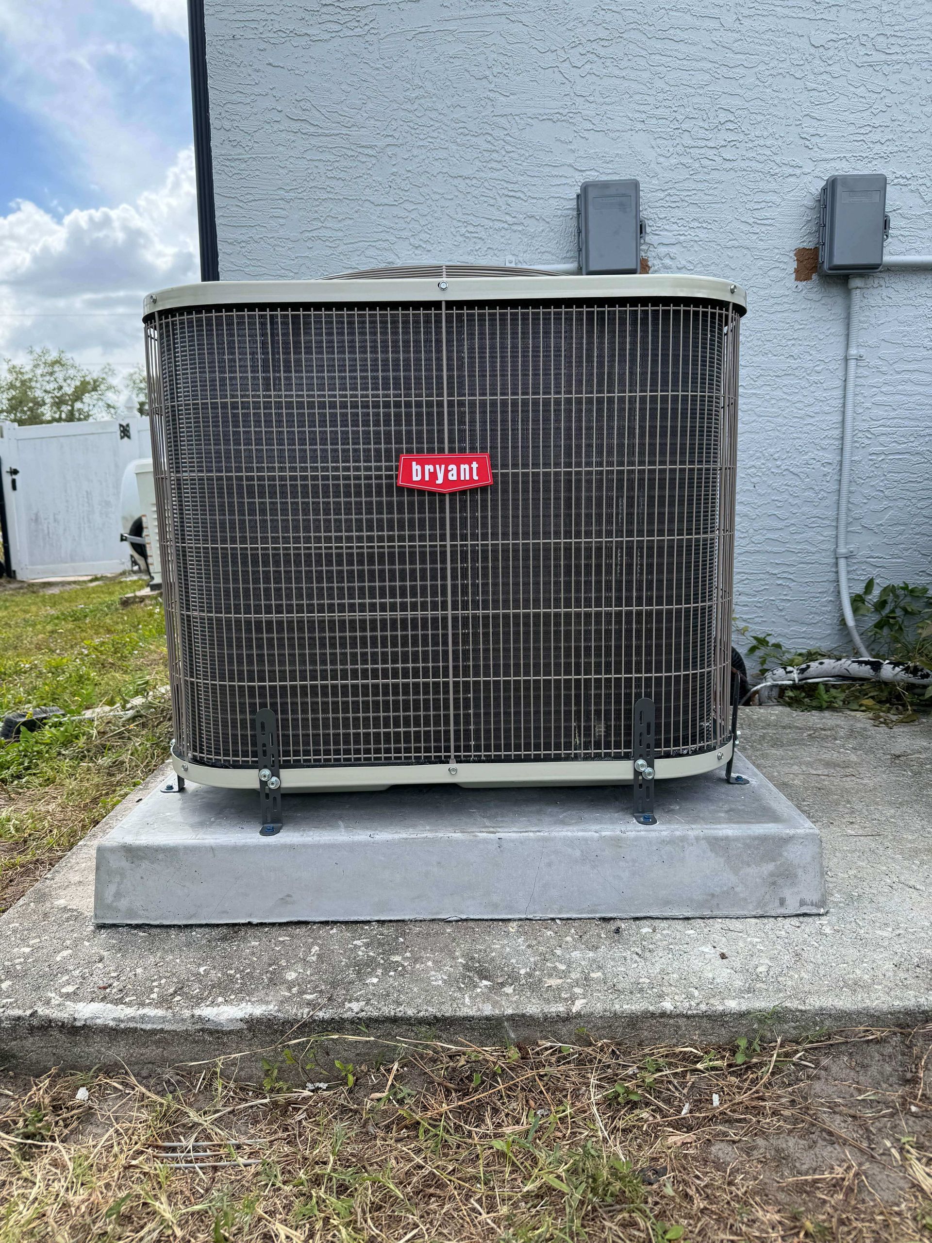 A large air conditioner is sitting on top of a concrete platform in front of a building.