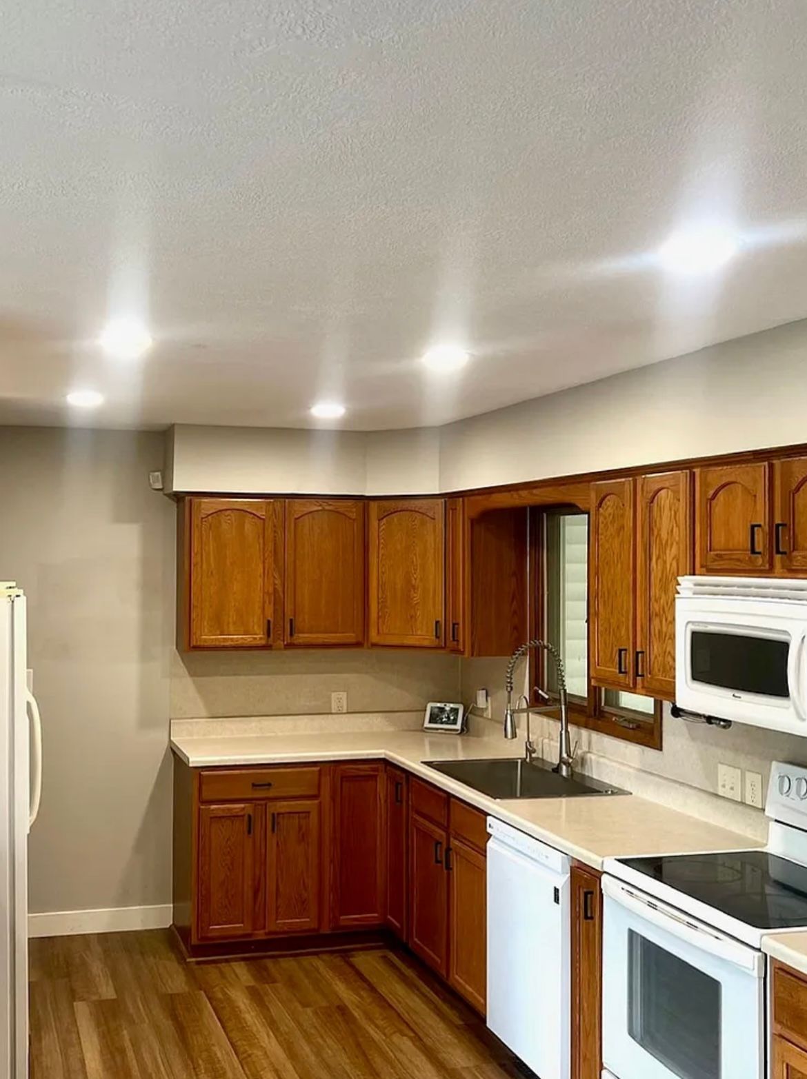 Kitchen with wooden cabinets, white appliances, and a window above the sink.