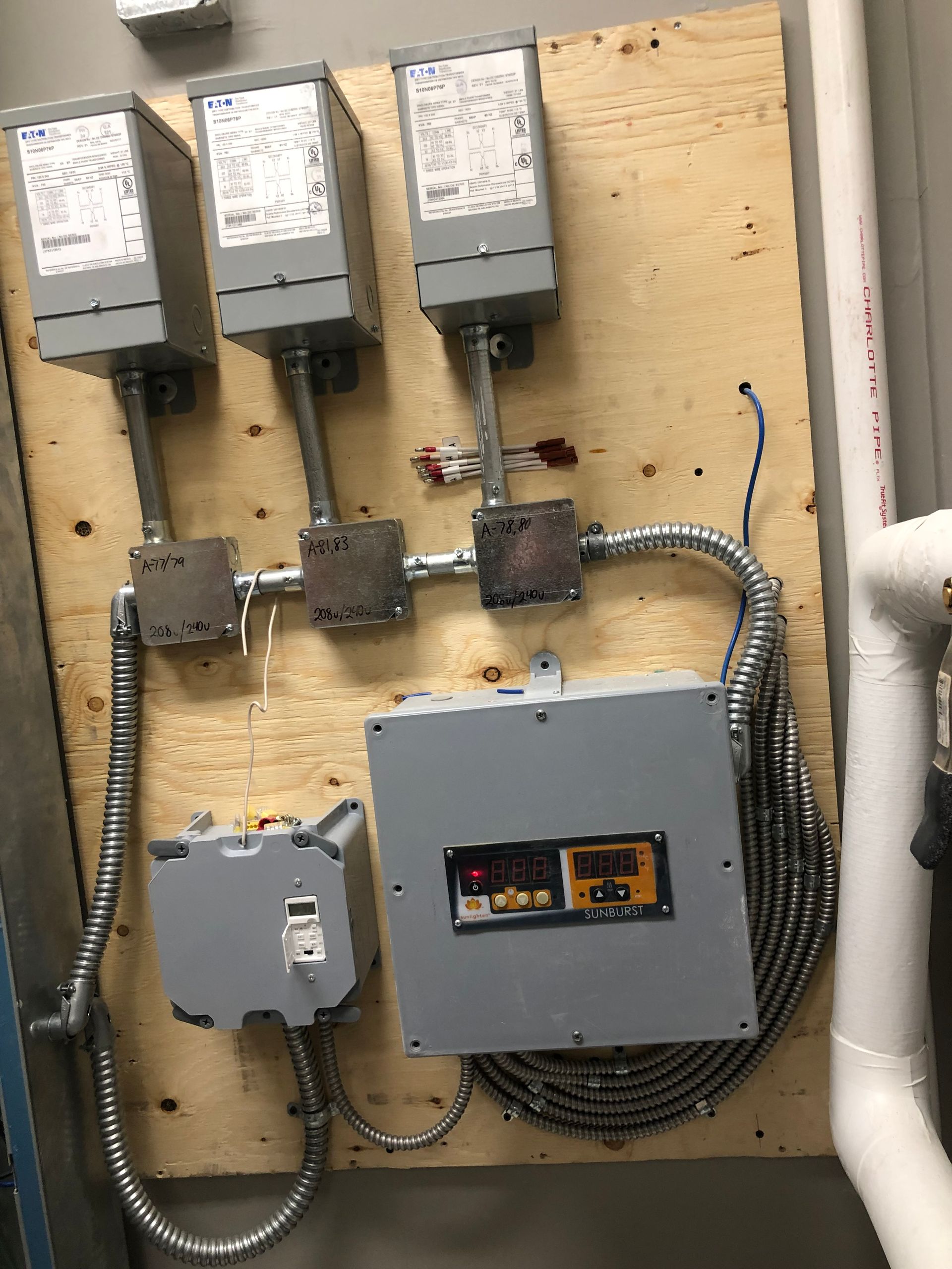 Electrical panel on wood backing with conduit and digital display.