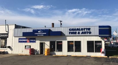 Two trucks are parked in front of a tire shop.