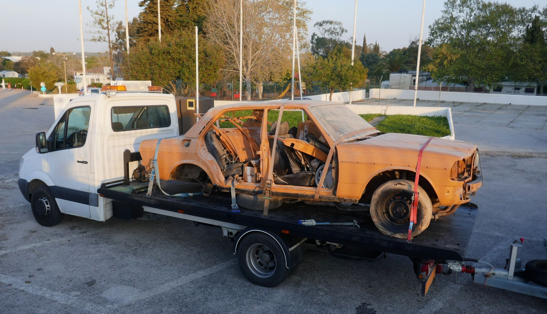 Junk car removal service provider transporting an old, broken, rusty car.