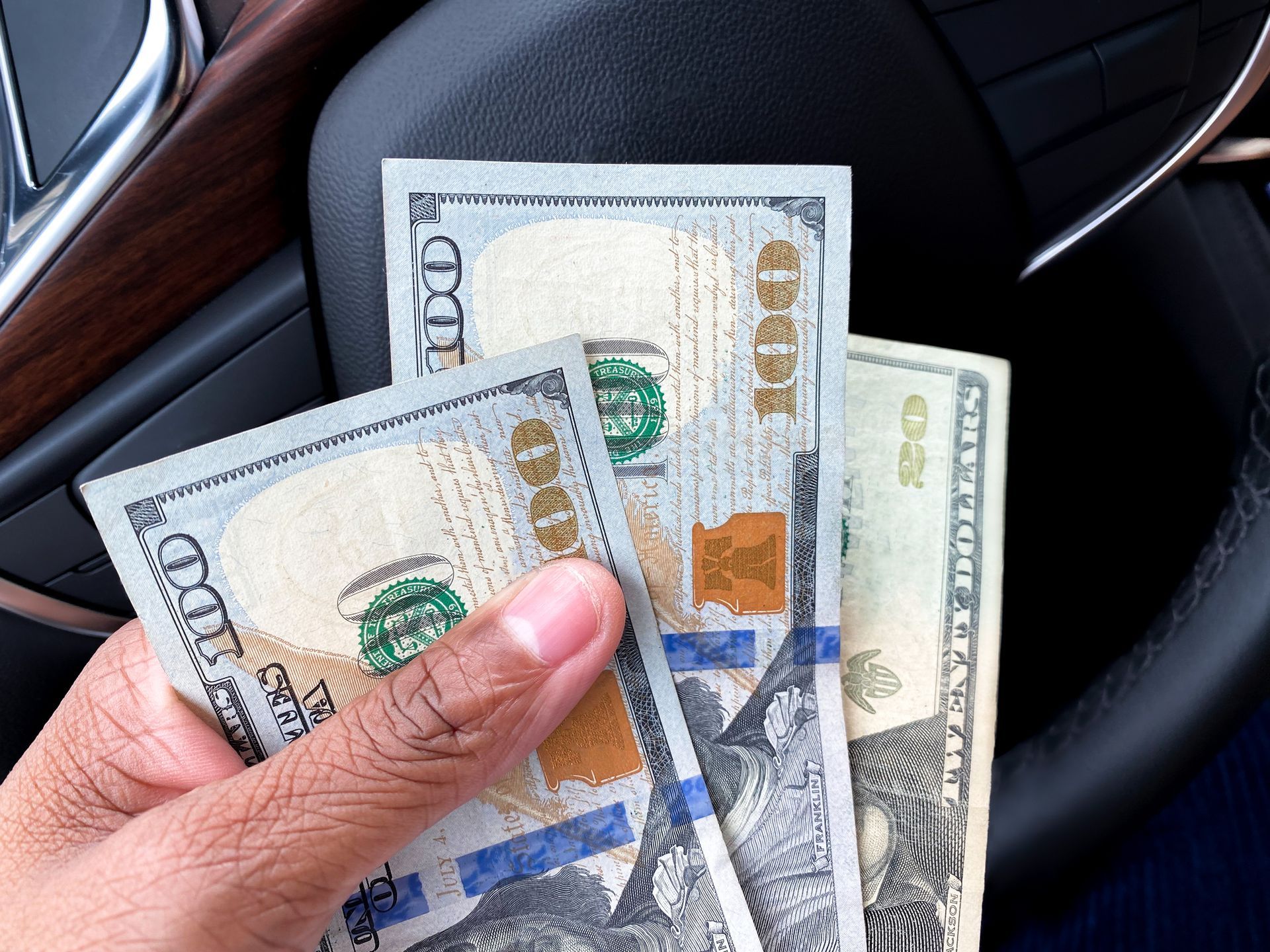 Hand holding cash over the wheel after selling a junk car.