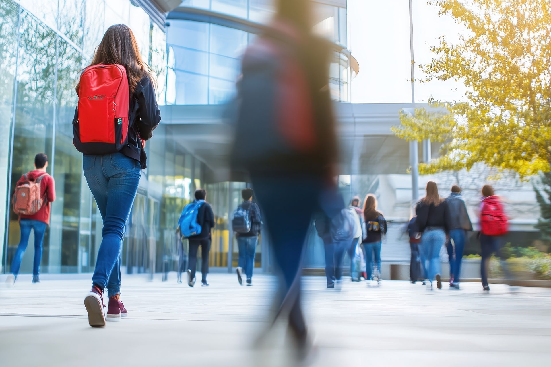 A group of students are walking down a sidewalk on their college campus.