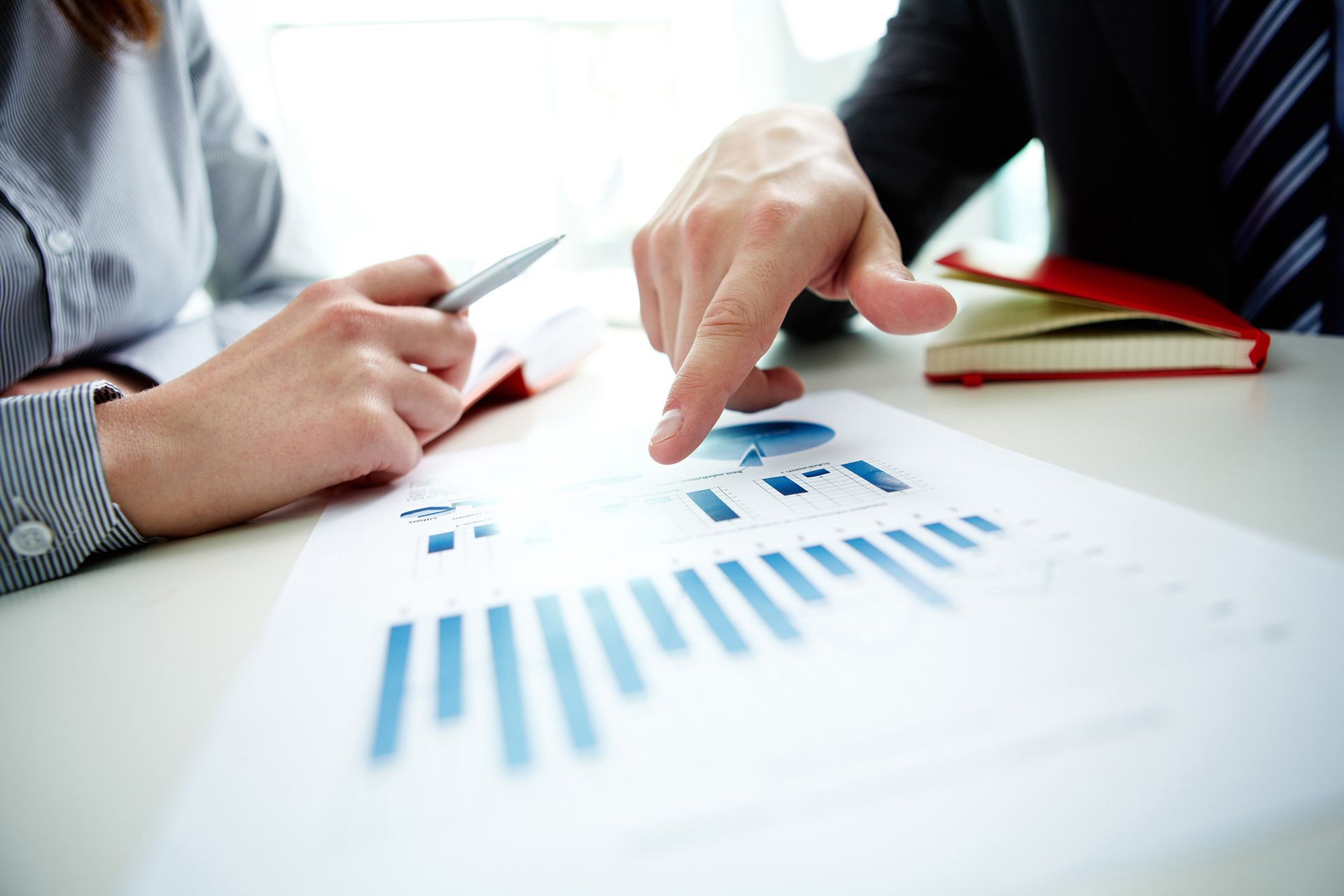 A man and a woman are looking at a graph on a piece of paper.