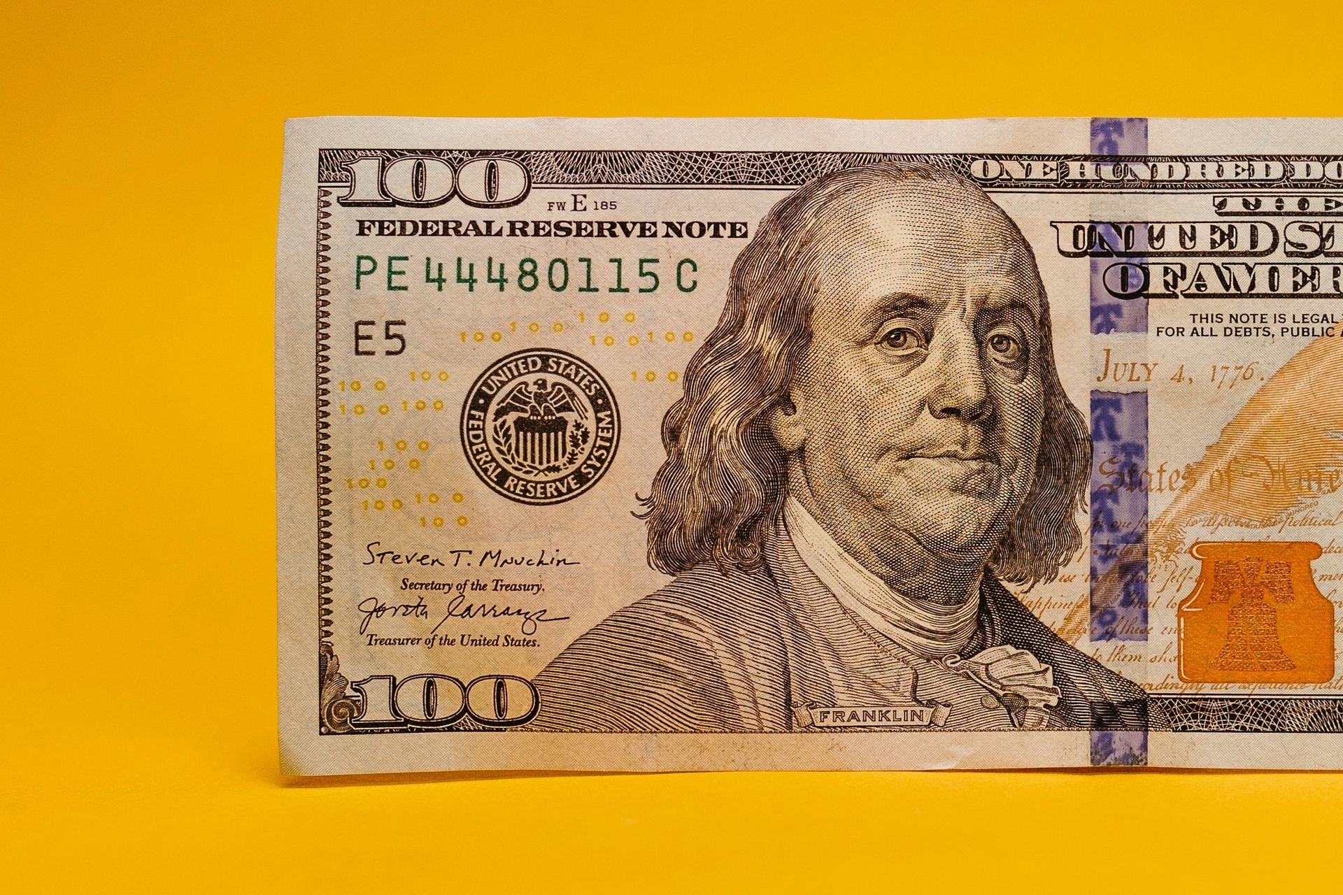a close up of a 100 dollar bill on a yellow background