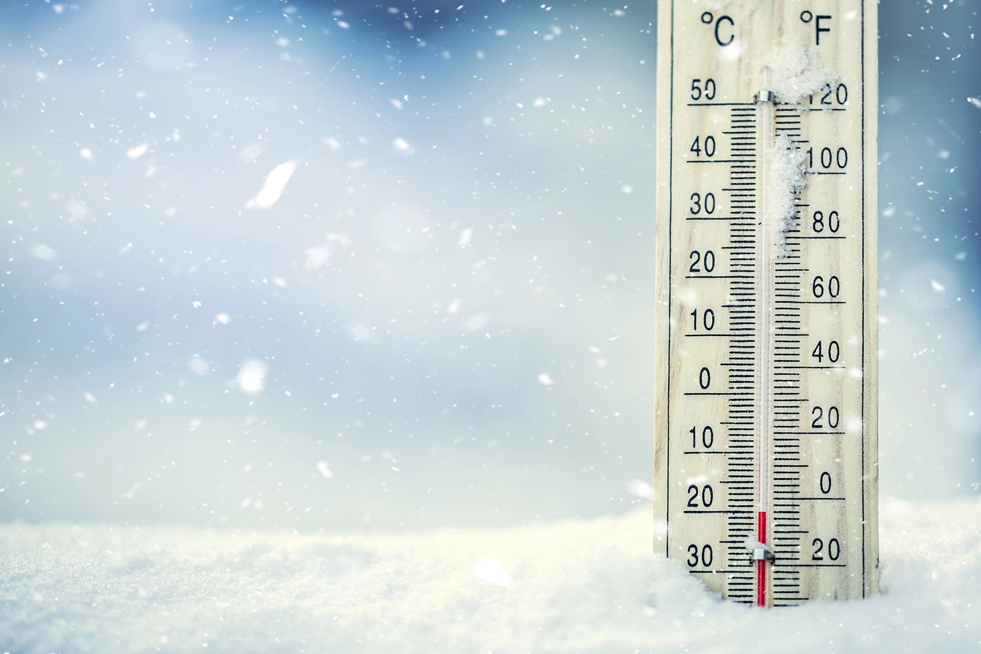 A thermometer is sitting in the snow and the temperature is below zero degrees fahrenheit.