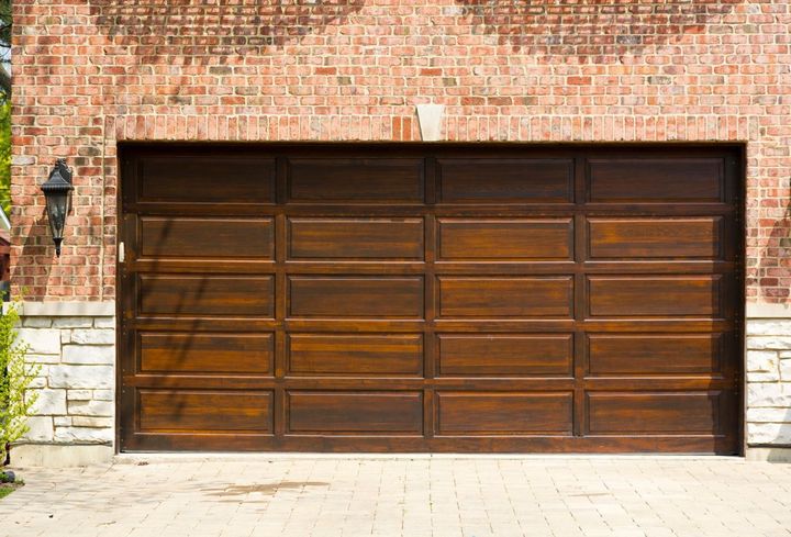 A wooden garage door is sitting in front of a brick building.