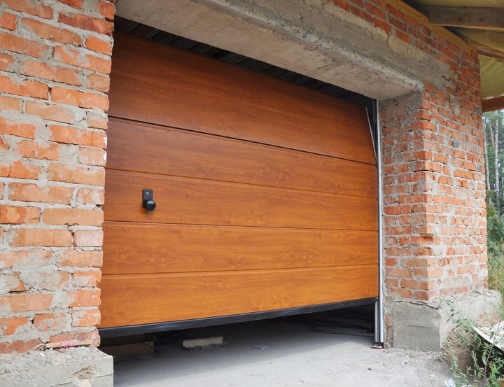 A wooden garage door is open in a brick building.