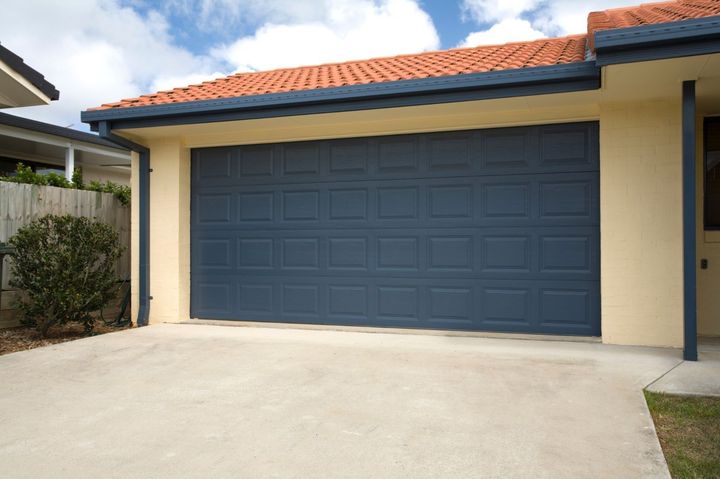 A blue garage door is sitting in front of a house.