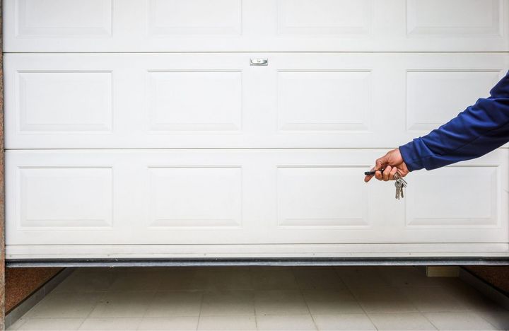 A person is opening a garage door with a key.