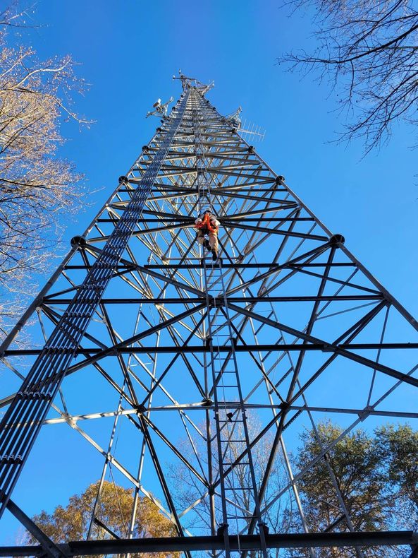 A person wearing a red helmet is climbing a metal structure.