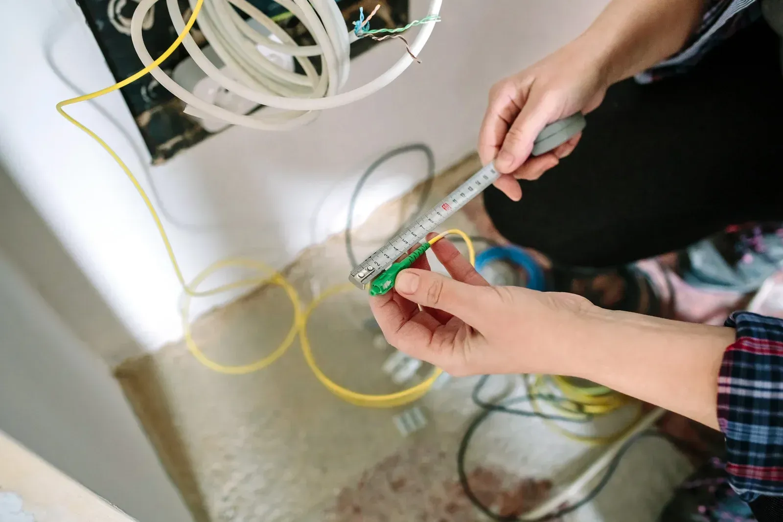 A person is measuring a wire with a tape measure.