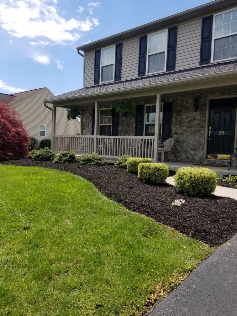 A house with a lush green lawn and black shutters