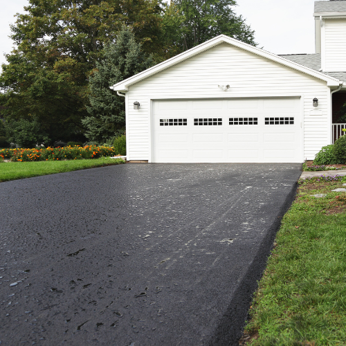 A white garage with a black driveway in front of it