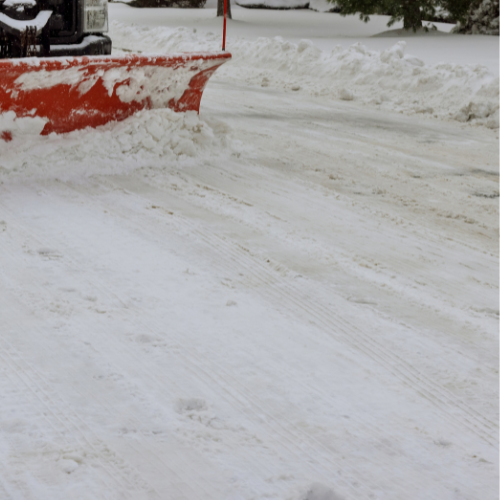 A snow plow is clearing snow from the road