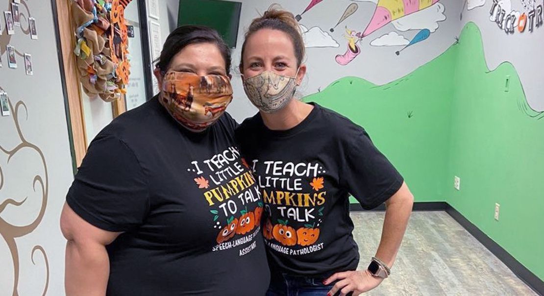 Two women wearing masks and matching t-shirts that read 