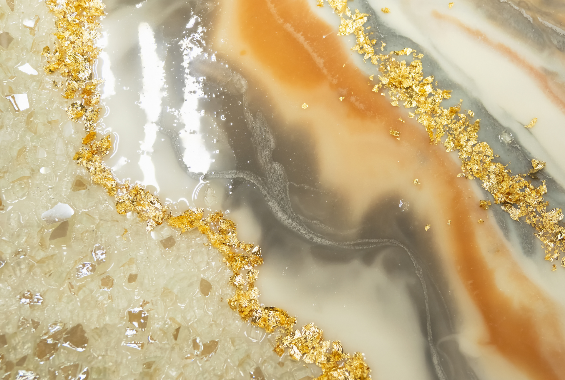 Abstract resin art with gold flecks, cream, gray, and orange swirls.