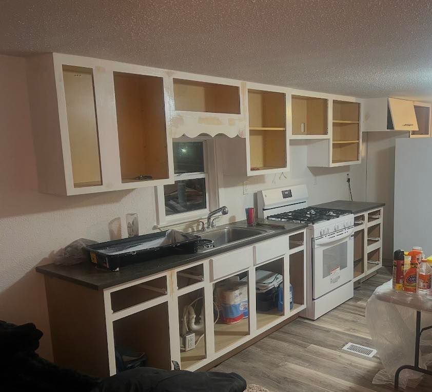 Woman in straw hat smiles, holding wine glass near a lake.