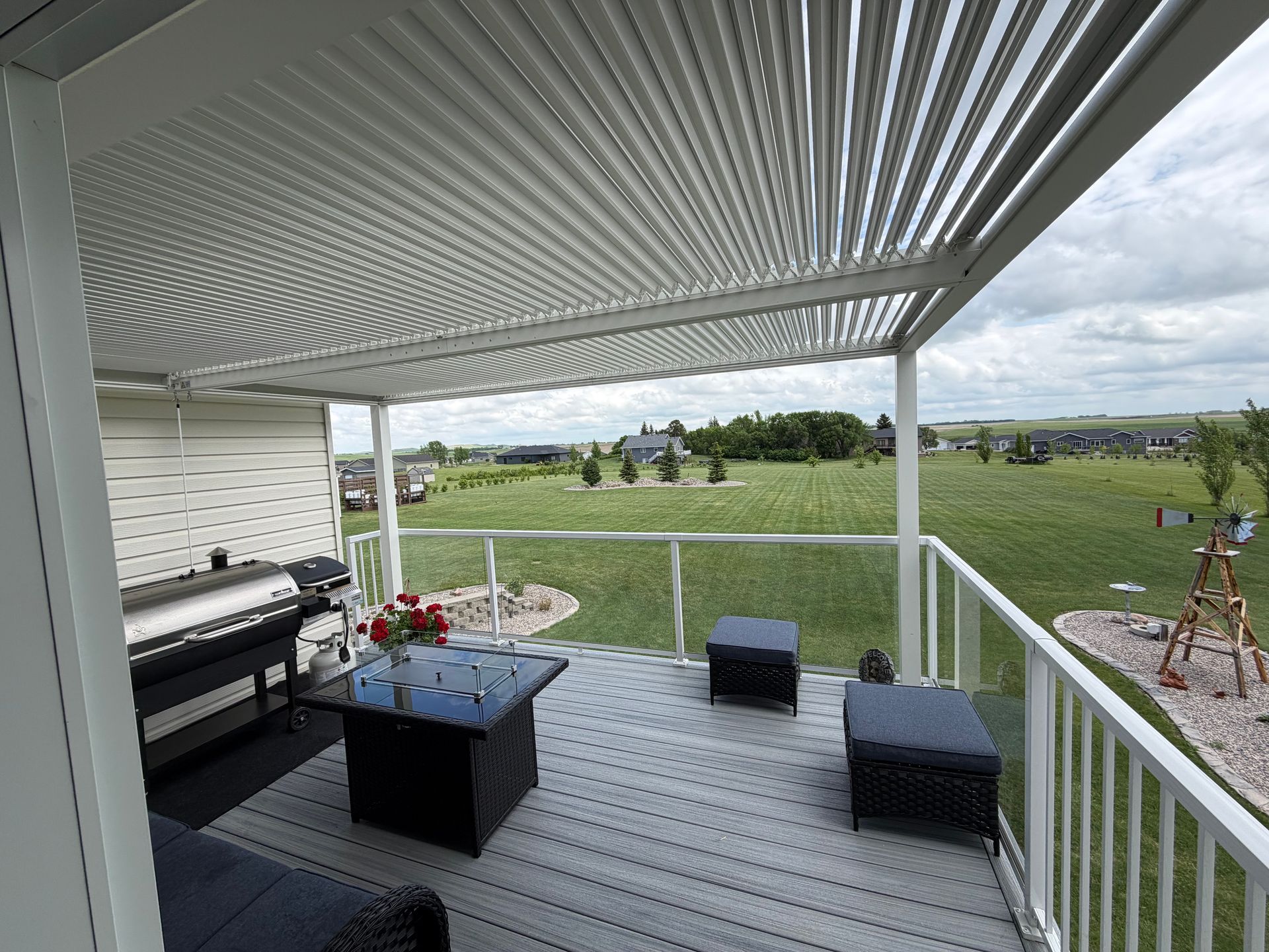 Covered patio with outdoor sofa and tables overlooking a green yard and open landscape