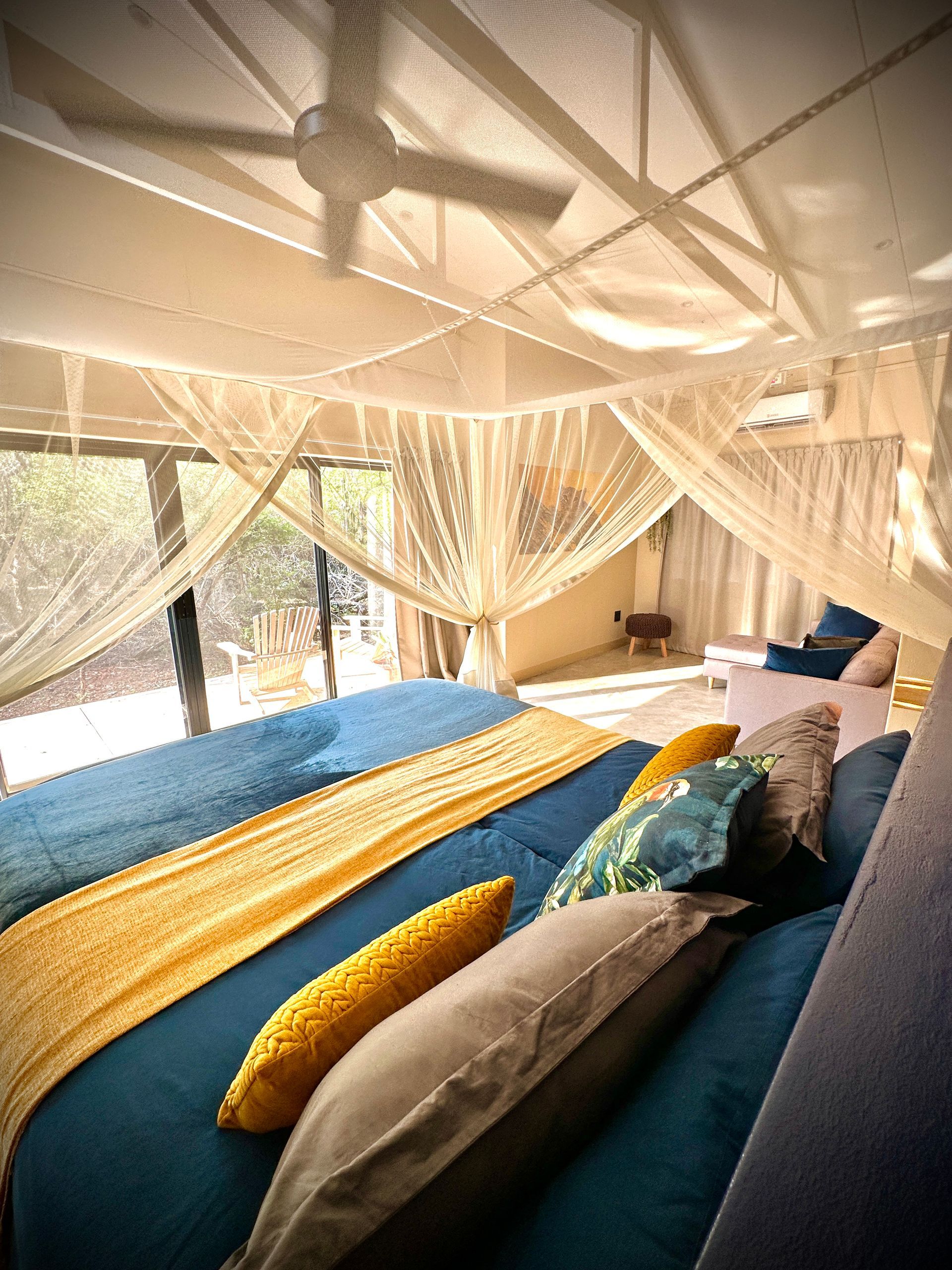 A bedroom with a king size bed , a couch , and a ceiling fan.