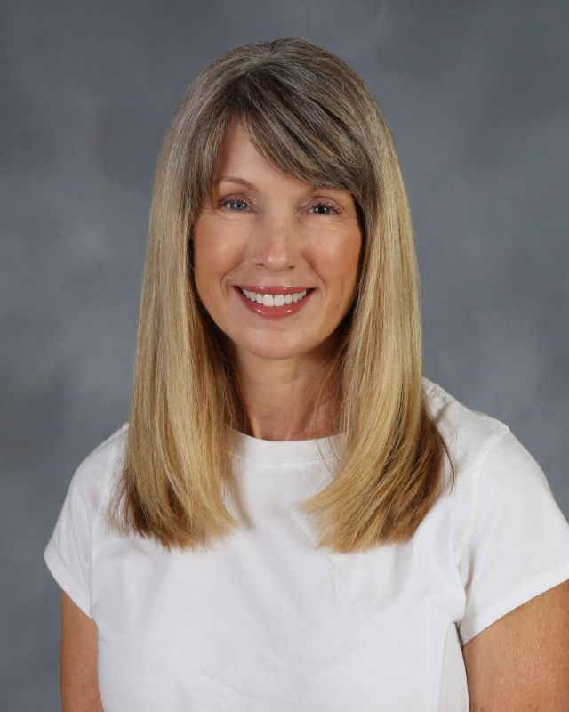 Woman with blonde hair and a white shirt smiles.