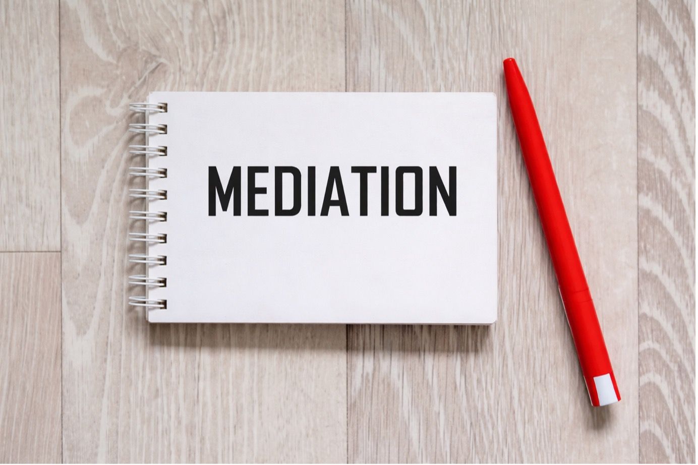Mediation concept with notebook and red pen on wooden desk