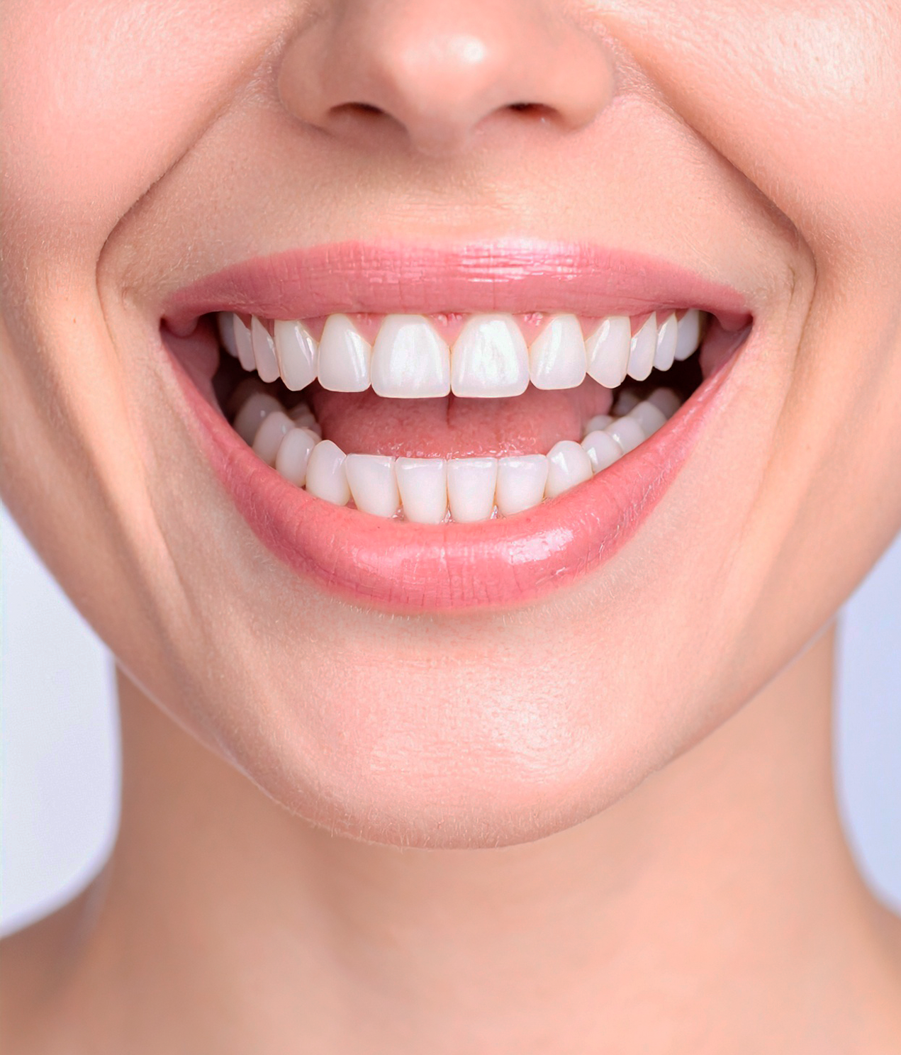 A close up of a woman 's smile with white teeth and pink lips.