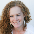 A woman with curly hair and earrings is smiling for the camera.