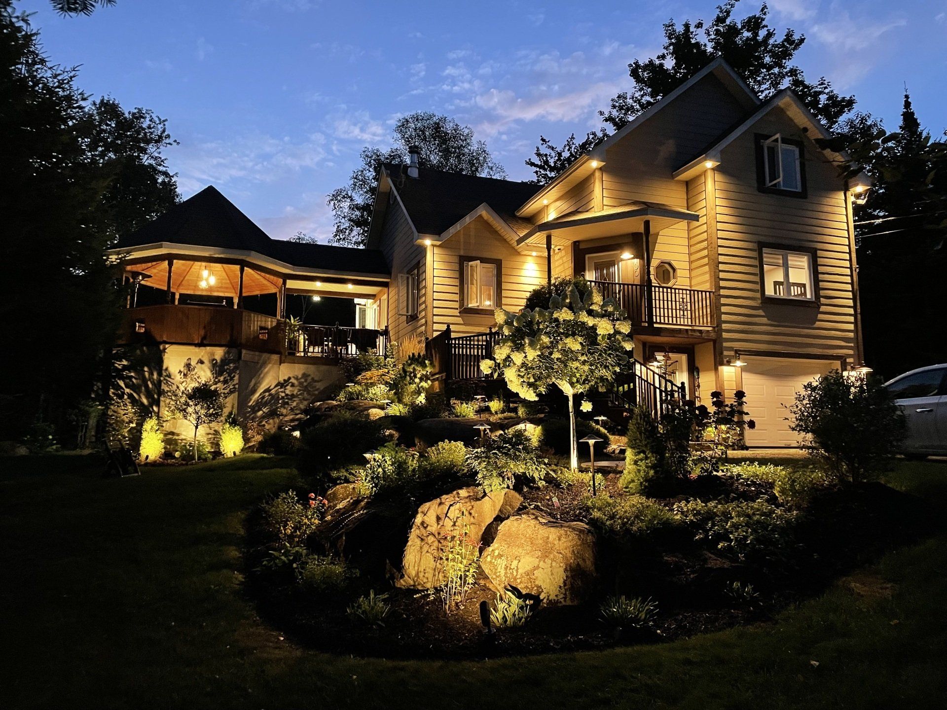 Une maison est éclairée la nuit avec une voiture garée devant
