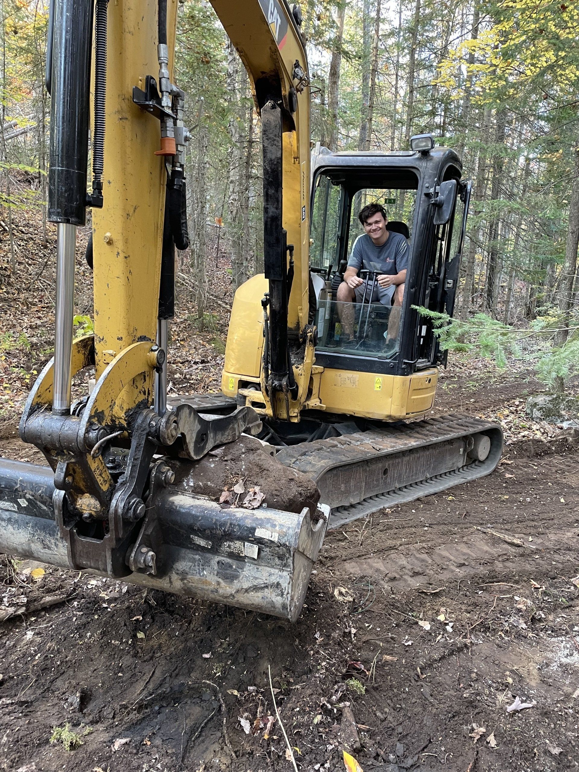 Un homme est assis sur le siège conducteur d'une excavatrice dans les bois.