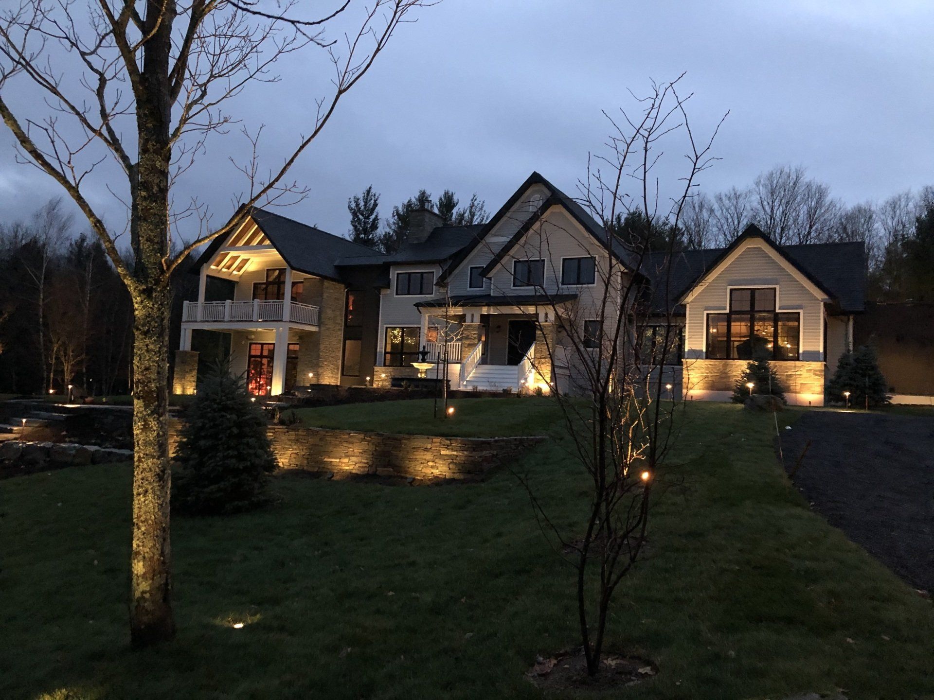 Une grande maison est éclairée la nuit avec des arbres devant elle