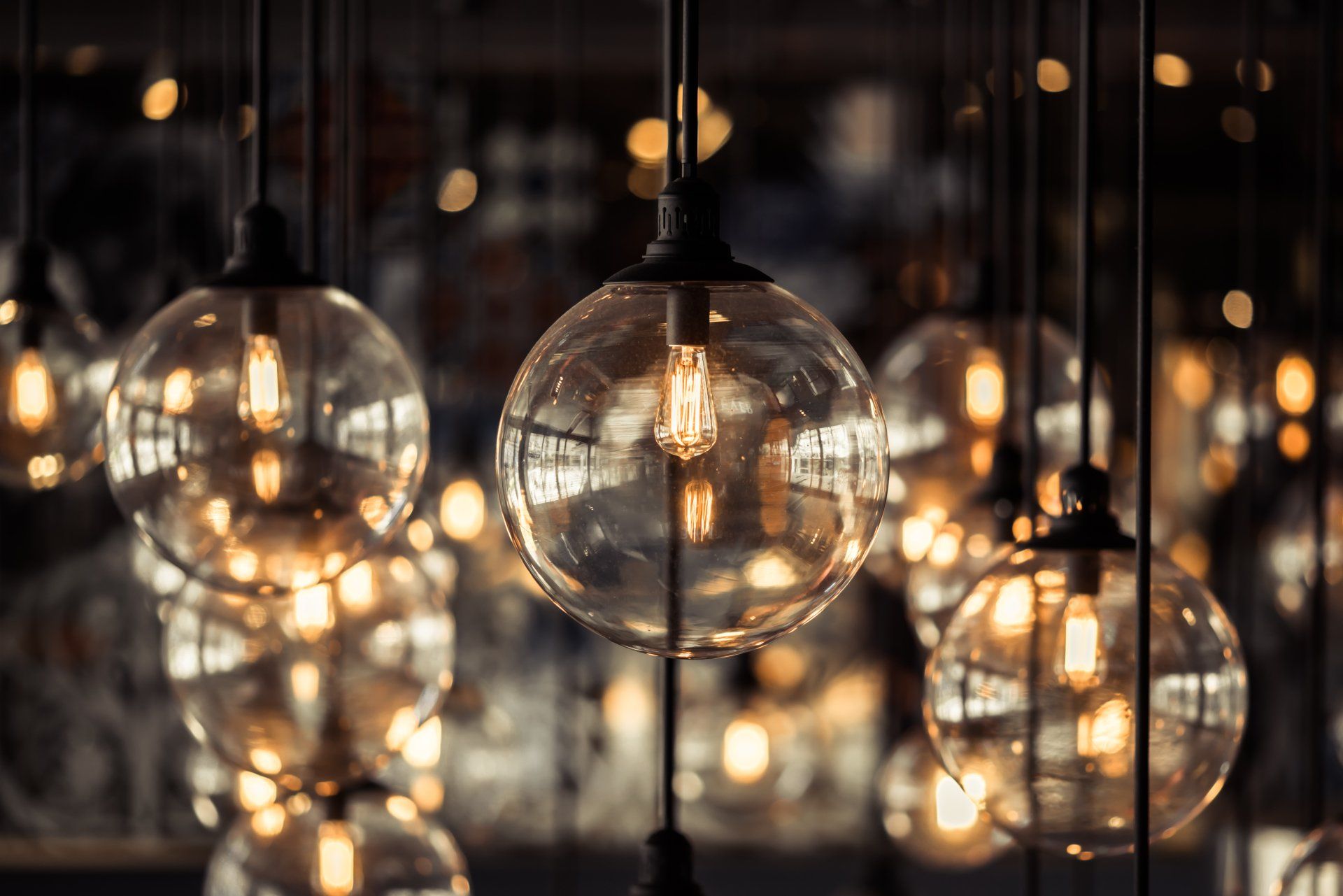 Vue aérienne de plusieurs ampoules sphériques allumées suspendues au plafond, créant une ambiance chaleureuse et accueillante.