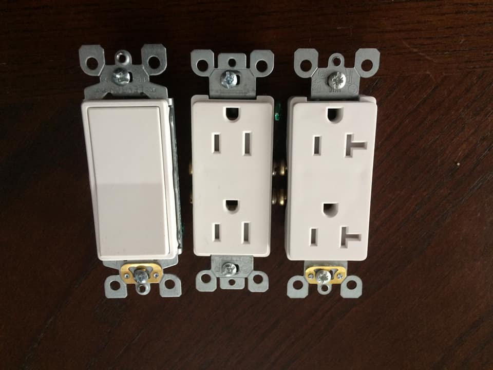 Trois prises électriques blanches et un interrupteur sur une table