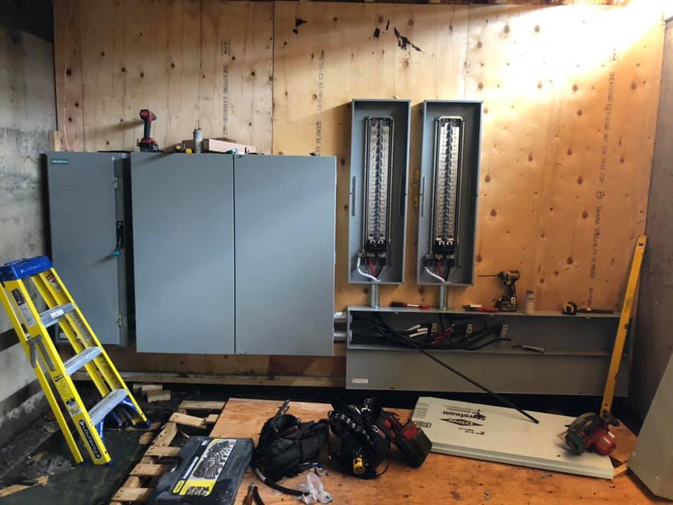 Une échelle est posée sur le sol dans une pièce avec des boîtiers électriques.